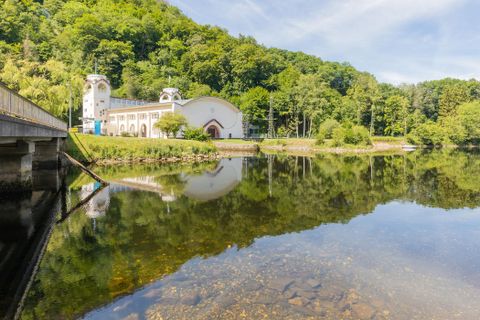 Un lac paisible reflète un bâtiment historique et des arbres verts. Les environs sont paisibles et idylliques.