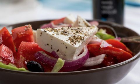 <p>Symbolbild- eine dunkle Salatschüssel gefüllt mit roter Paprika, roten Zwiebeln, grünem Salat und Oliven.Auf dem Salat liegt ein dreieckiges Stück weißer Käse.</p>