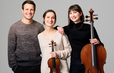 Eine Musikerin sitzt auf einer Bank und hält eine Gitarre. Sie trägt ein elegantes Outfit und schaut in die Kamera.