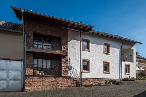 Ein modernes Wohnhaus mit einer Kombination aus weißem Putz und Steinmauer. Die Fassade hat große Fenster und einen einladenden Eingangsbereich.