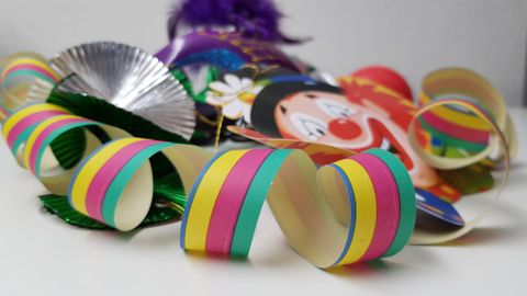 Colorful carnival decorations with a clown mask and colorful streamers. The celebrations are approaching.