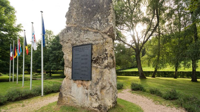 European monument at the Ouren border triangle with flags and memorial plaque.