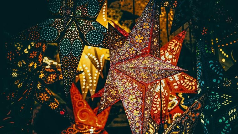 Une collection colorée d'étoiles en papier lumineuses. Les étoiles ont des motifs délicats et brillent dans différentes couleurs.