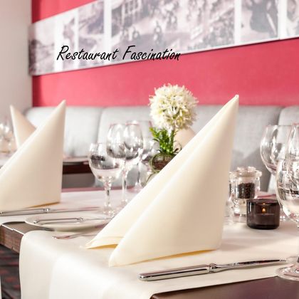 Un restaurant élégant avec des tables joliment dressées et des meubles modernes. De grandes fenêtres laissent entrer beaucoup de lumière et offrent une vue sur les environs.