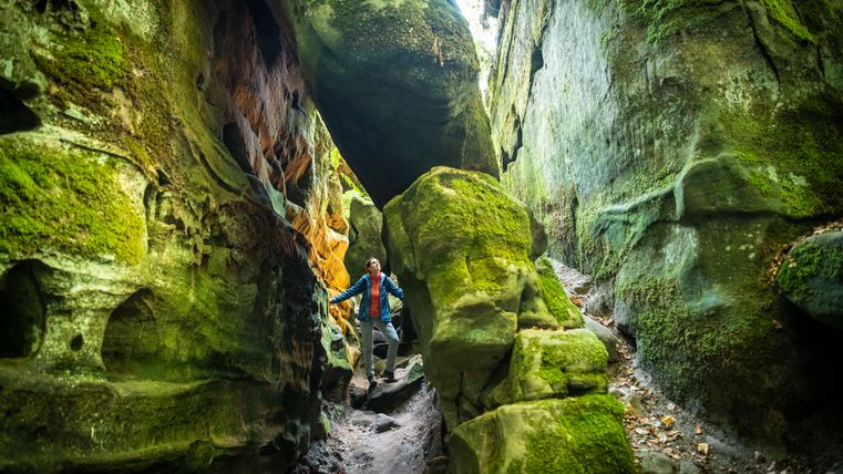 Persoon in een met mos bedekte rotsachtige kloof.