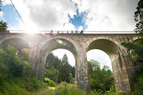 Fietsers op het Reichenstein viaduct van de Vennbahn in de zon.