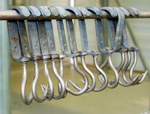 Eine Reihe von Metallhaken hängt an einer Stange. Sie sind zur Befestigung und Aufhängung von Objekten geeignet.