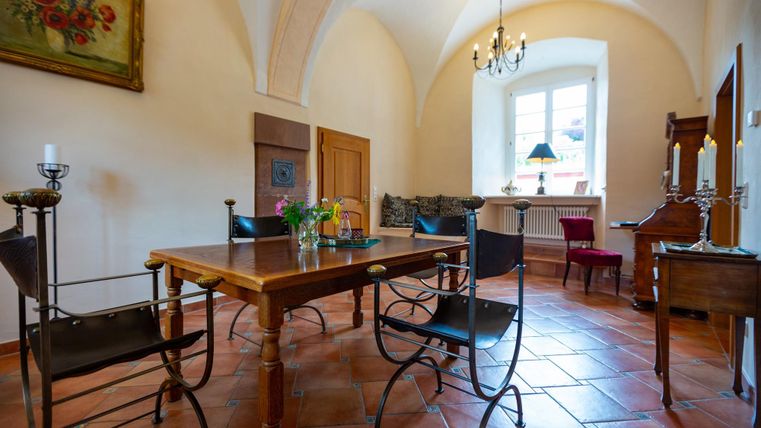 Ein einladender Raum mit einem Holztisch und eleganten Stühlen. Sanfte Farben und ein gemütlicher Stil schaffen eine entspannte Atmosphäre.