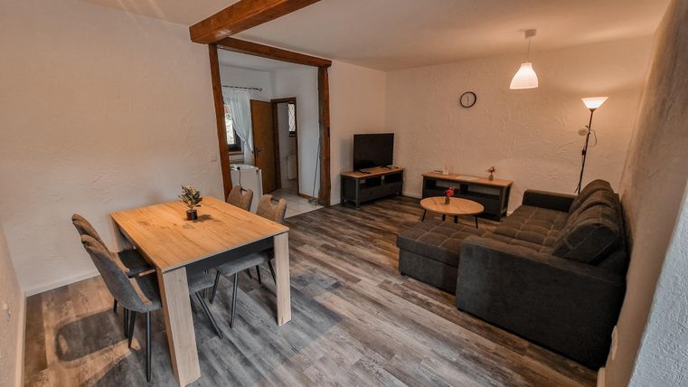 Ein modernes Wohnzimmer mit einem Sofa und einem Tisch. Der Raum hat helles Holz und sanfte Beleuchtung.