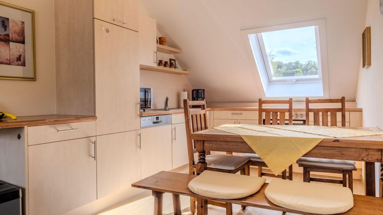 Vakantiewoning Veldmuis - Een lichte keuken met moderne meubels en een houten eetgedeelte. Het raam laat veel daglicht binnen en biedt uitzicht op buiten.