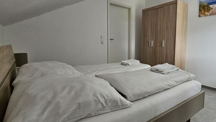 Une chambre confortable avec un lit double et des serviettes fraîches. À l'arrière-plan, il y a une armoire en bois à côté d'une porte.