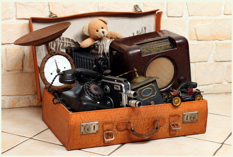 Ein vintage Koffer voller alter Gegenstände, darunter eine Kamera, eine Uhr, ein Plattenspieler und ein teddy. Der Koffer vermittelt ein Gefühl von Nostalgie und Geschichte.