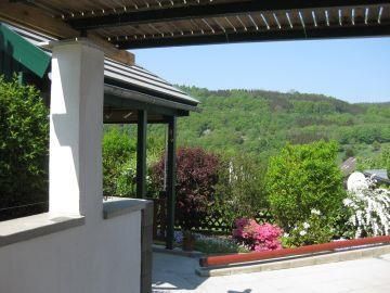 Een mooi uitzicht op een groene landschap met kleurrijke bloemen en struiken. Op de voorgrond is een overdekte ruimte te zien.