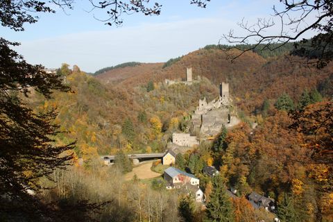 View of the Manderscheid castles in autumn with colorful foliage and surrounding hills.