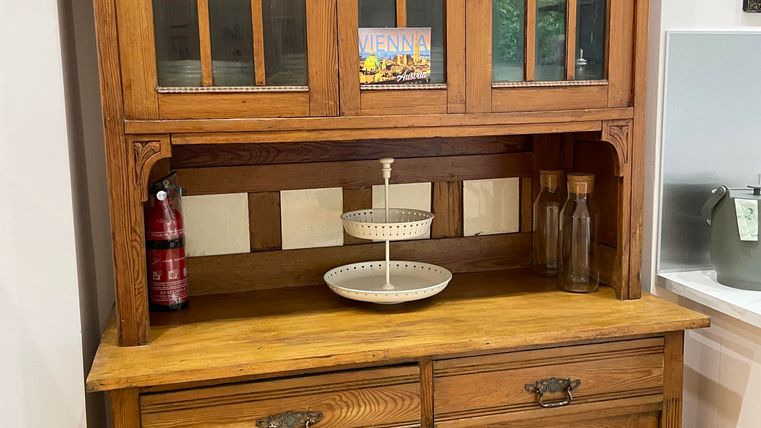 Une belle armoire de cuisine vintage en bois avec des fenêtres en verre. Elle possède une unité supérieure et une unité inférieure avec de l'espace de rangement et de la décoration.