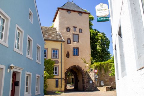 Historisches Stadttor in Dudeldorf mit angrenzenden Häusern und Straßenschild.