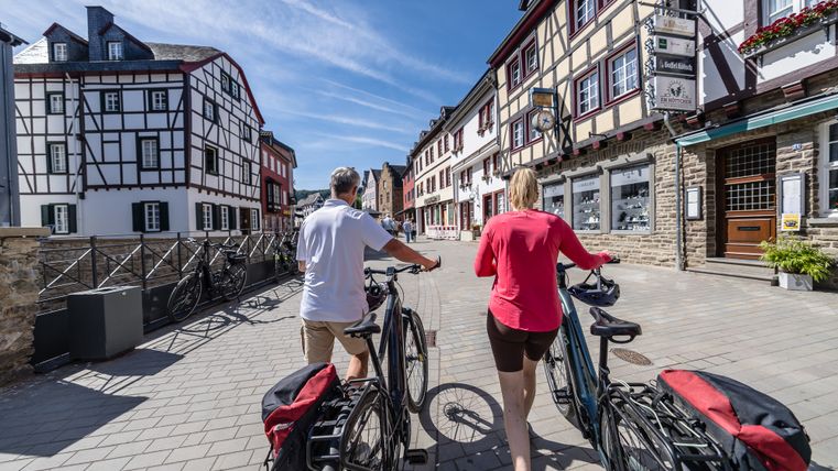 Deux personnes poussent des vélos dans une rue historique de Bad Münstereifel.