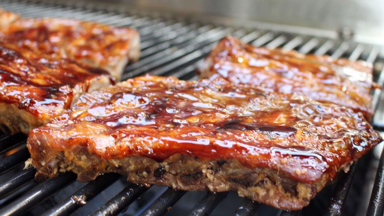 Gegrilde vlees met een glanzende marinade op een grillrooster. Heerlijke BBQ-ribs in een smakelijke kleur.