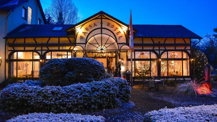 A charming hotel in winter with snow-covered ground. The facade is illuminated and radiates an inviting atmosphere.