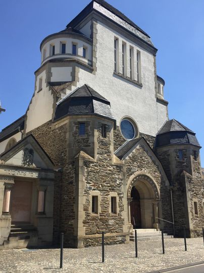 Een historische kerk met een markante gevel en een mooi dak. De lucht is helder en blauw.