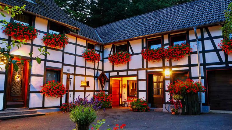 Een pittoresk vakwerkhuis met kleurrijke bloembakken en een gezellige binnenplaats. De sfeer is uitnodigend en charmant.