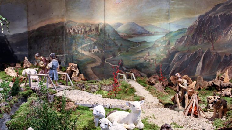 Une vue de scène avec des éléments de paysage, des figures et des ours en peluche blancs. À l'arrière-plan, un paysage de montagnes pittoresque avec un ciel dégagé est visible.