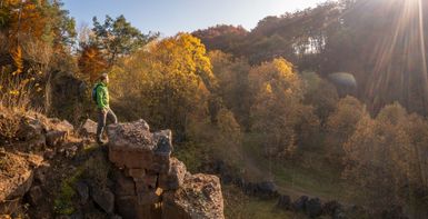 Ein Mann steht auf einem Steinbruch im herbstlichen Licht