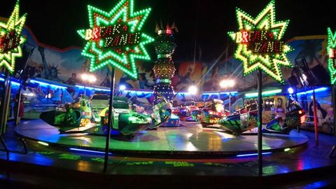 Un marché coloré avec un manège plein de lumières. Les étoiles brillantes et les véhicules colorés créent une atmosphère joyeuse.