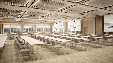 Une salle de conférence moderne avec de grandes tables et plusieurs chaises. De grandes fenêtres laissent entrer beaucoup de lumière naturelle.