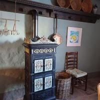 A traditional stove stands in a cozy room. Next to it are a chair, a basket, and some decorative elements on the wall.