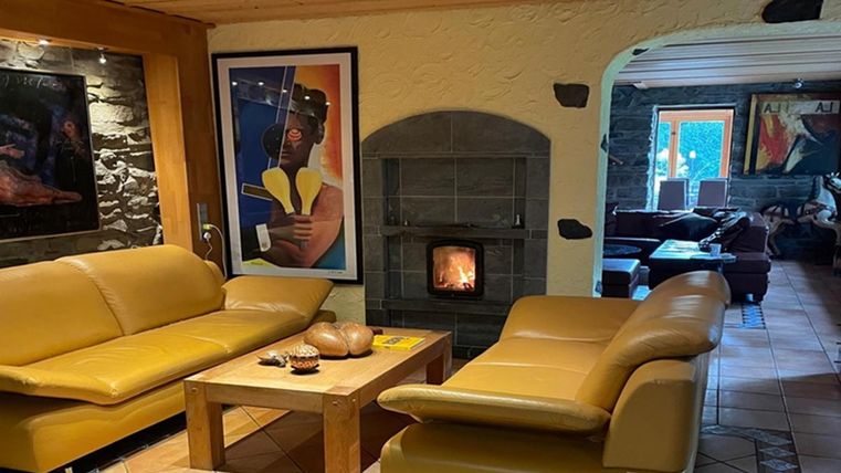 A cozy living room with two yellow sofas and a table. In the background, there is a fireplace and colorful artworks on the walls.