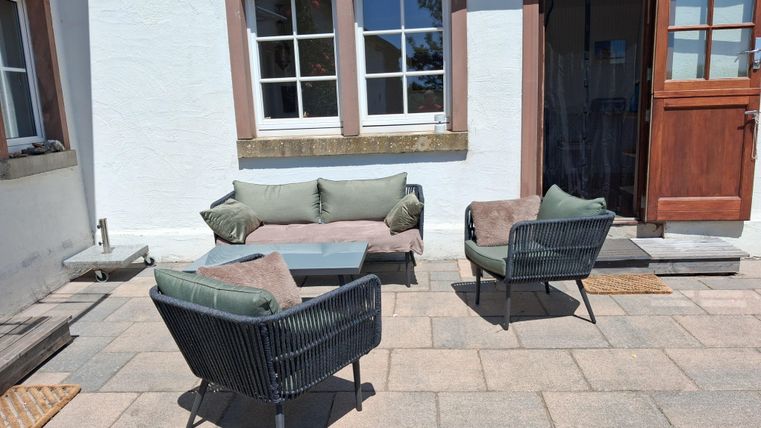 Une terrasse confortable avec des meubles modernes. Les rayons du soleil filtrent à travers les fenêtres et créent une atmosphère accueillante.