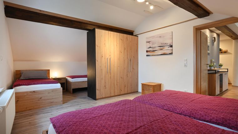 Ein gemütliches Schlafzimmer mit zwei Betten und einem Holzschrank. Es gibt ein warmes Ambiente mit sanfter Beleuchtung und modernem Design.