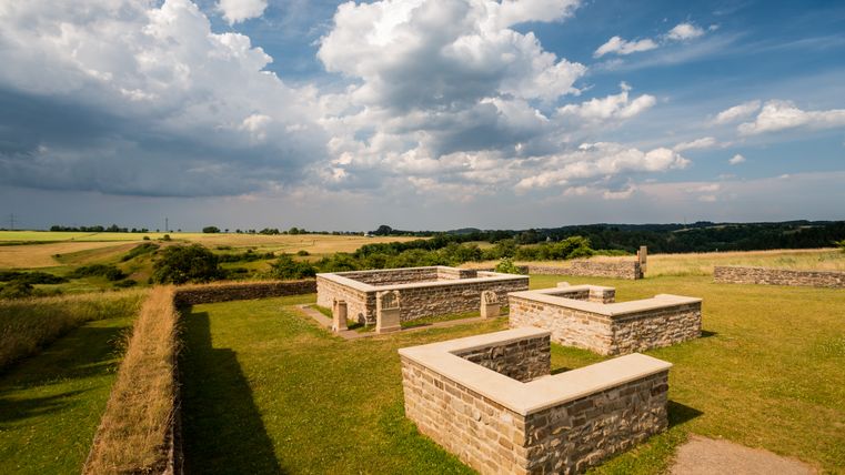 Sanctuaire des matrones de Görresburg dans l'Eifel, entouré de champs verts et d'un ciel nuageux.