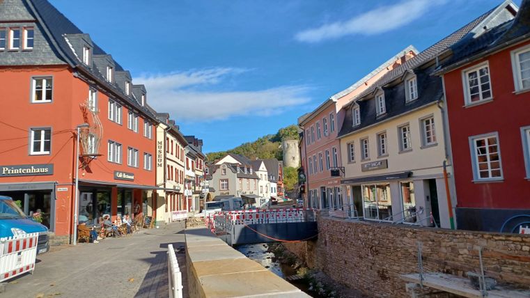 Scène de rue à Bad Münstereifel avec des bâtiments historiques et une petite rivière.