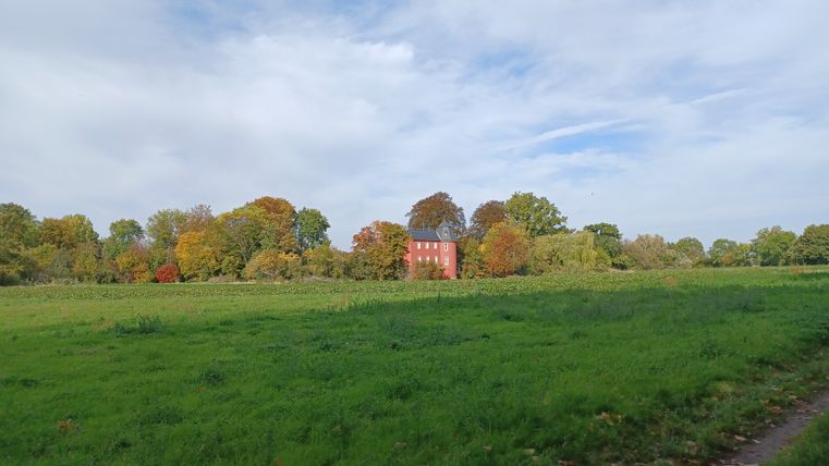 Kasteel Kessenich achter een groene weide en bomen in de herfst.
