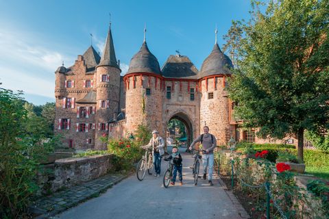 Famille avec des vélos devant le château de Satzvey.
