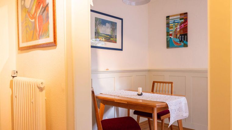 Une salle à manger confortable avec une table en bois et des chaises. Des œuvres d'art colorées sont accrochées au mur.