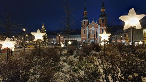 Eine festlich dekorierte Stadt mit leuchtenden Sternen im Vordergrund. Im Hintergrund steht eine schöne Kirche bei Nacht.