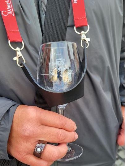 A man is holding a glass with a black holder. The glass is decorated with a logo.