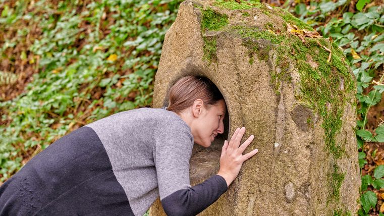 A person puts their head into a humming stone on the Kleine Kyll mindfulness trail.