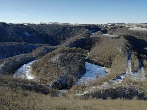 Winter landscape with river and hills, partly covered in snow.